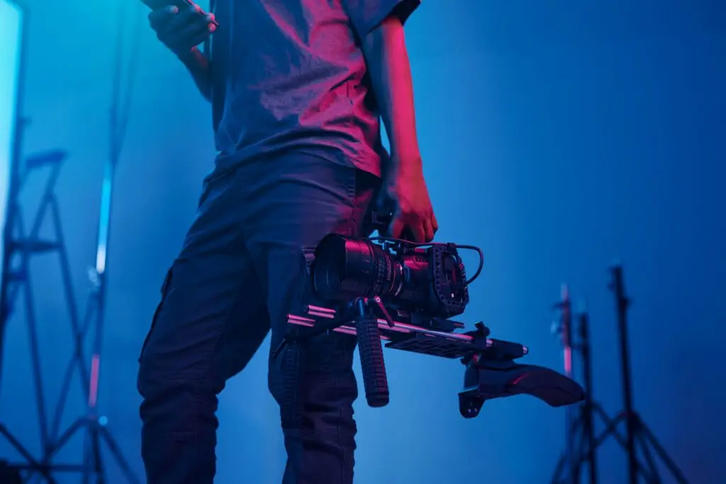 Professionele fotograaf met camera rig in een studio met blauw licht, illustreert Toméci Fotografie diensten.
